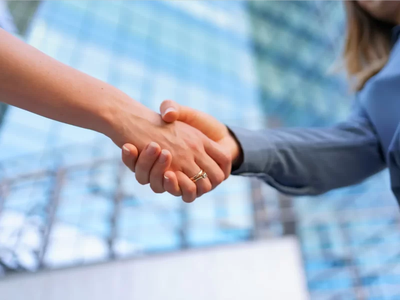 woman-handshaking-outdoors-modern-glass-business-building-close-up-picture.webp
